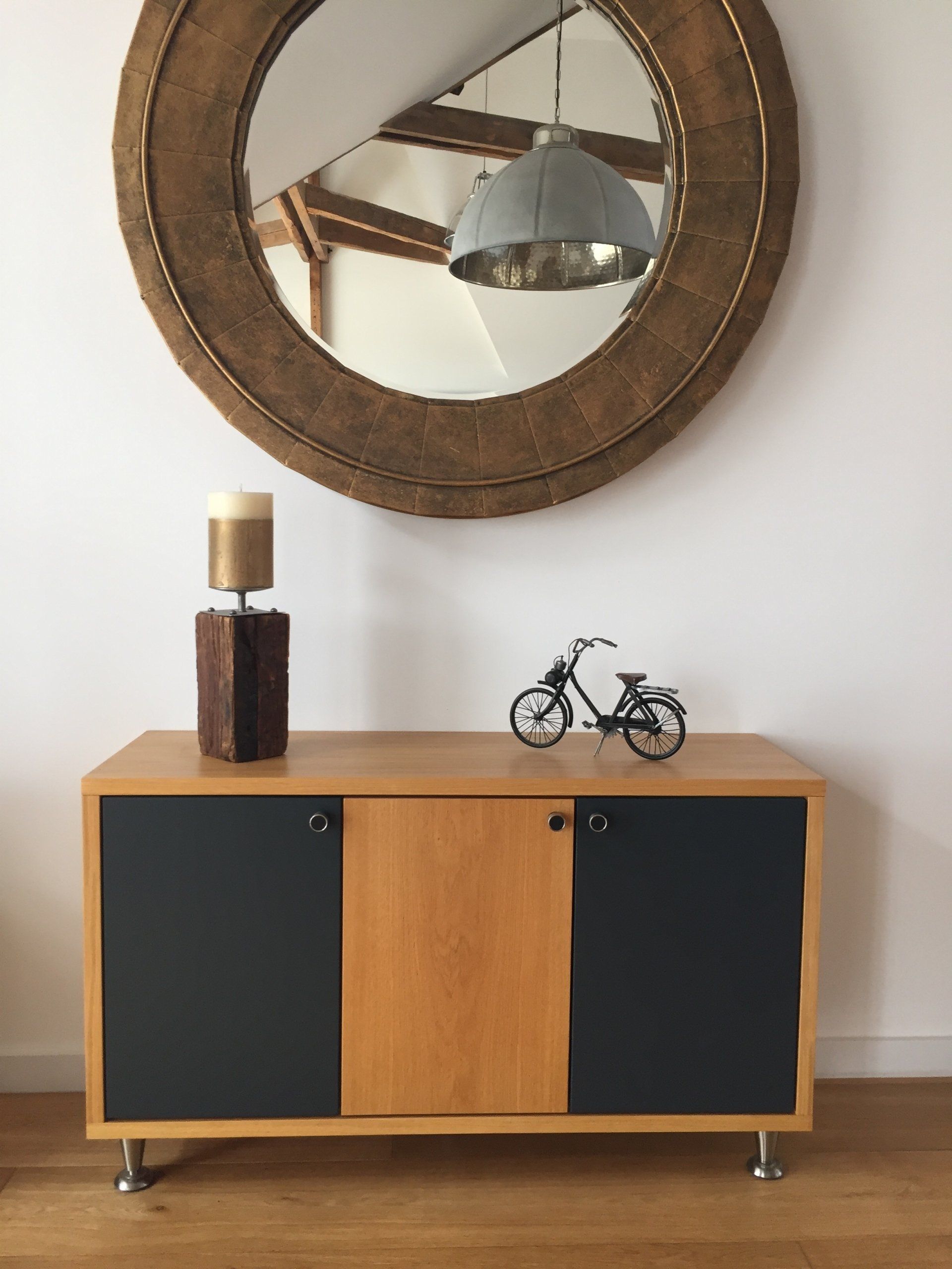 A wooden cabinet with a bicycle on top of it under a large mirror.