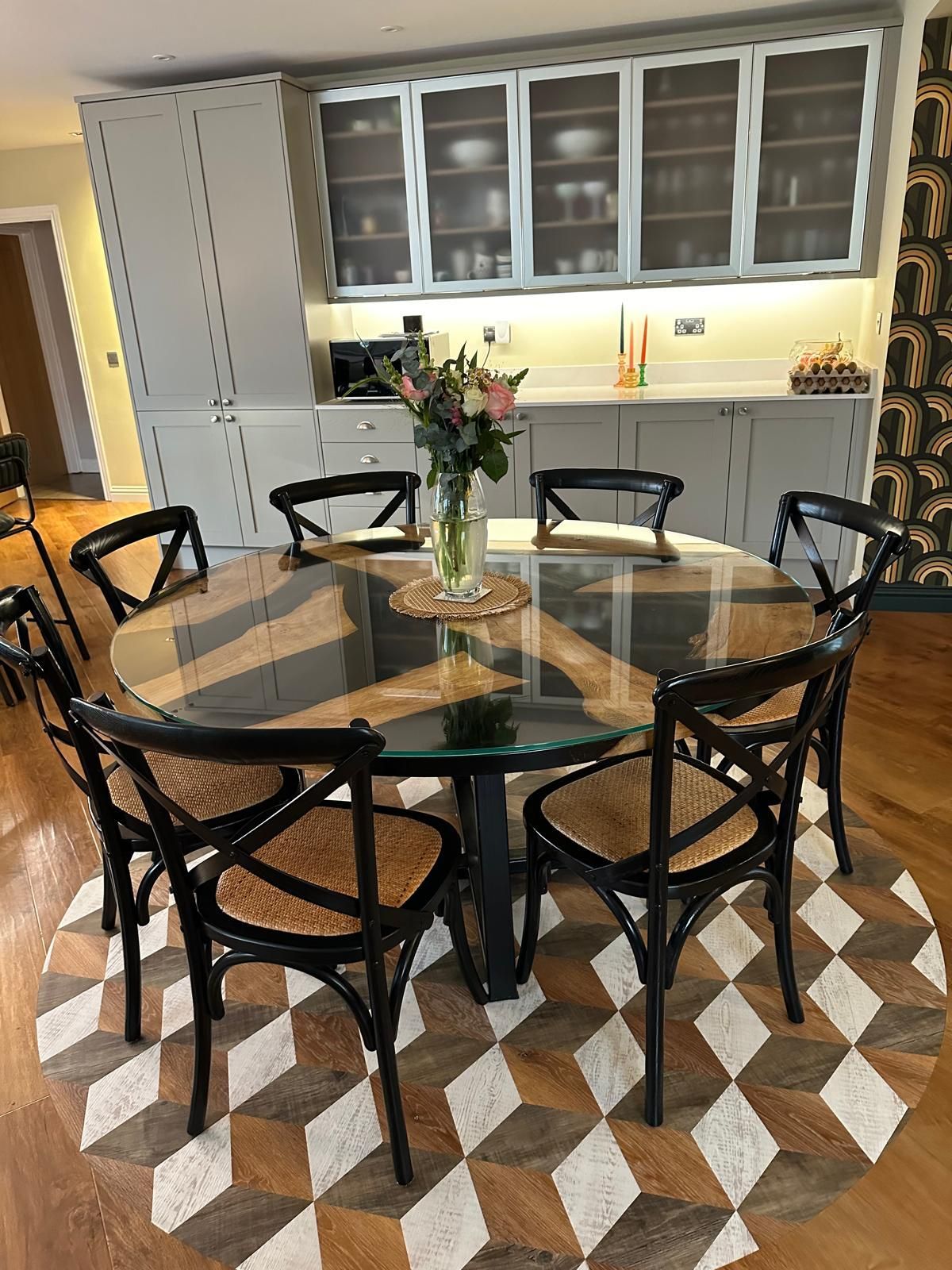 A dining room with a glass table and chairs and a checkered rug.