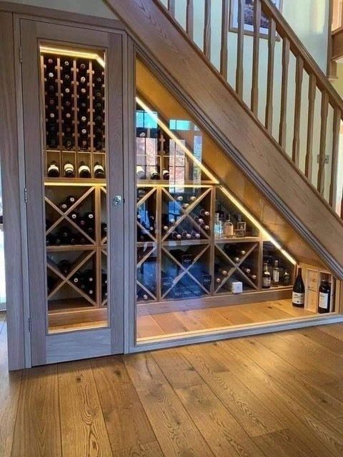 A wine cellar under a staircase with bottles on shelves