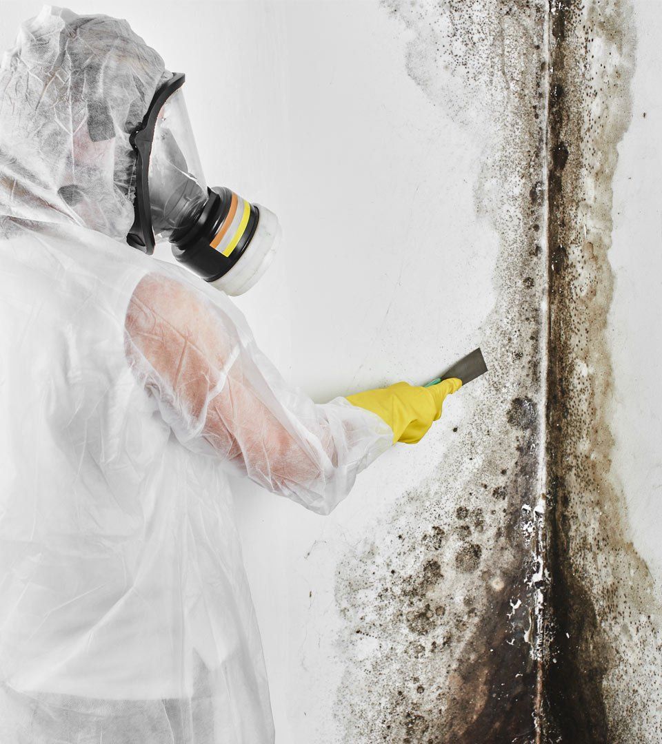 a person wearing a gas mask and gloves is cleaning a wall .