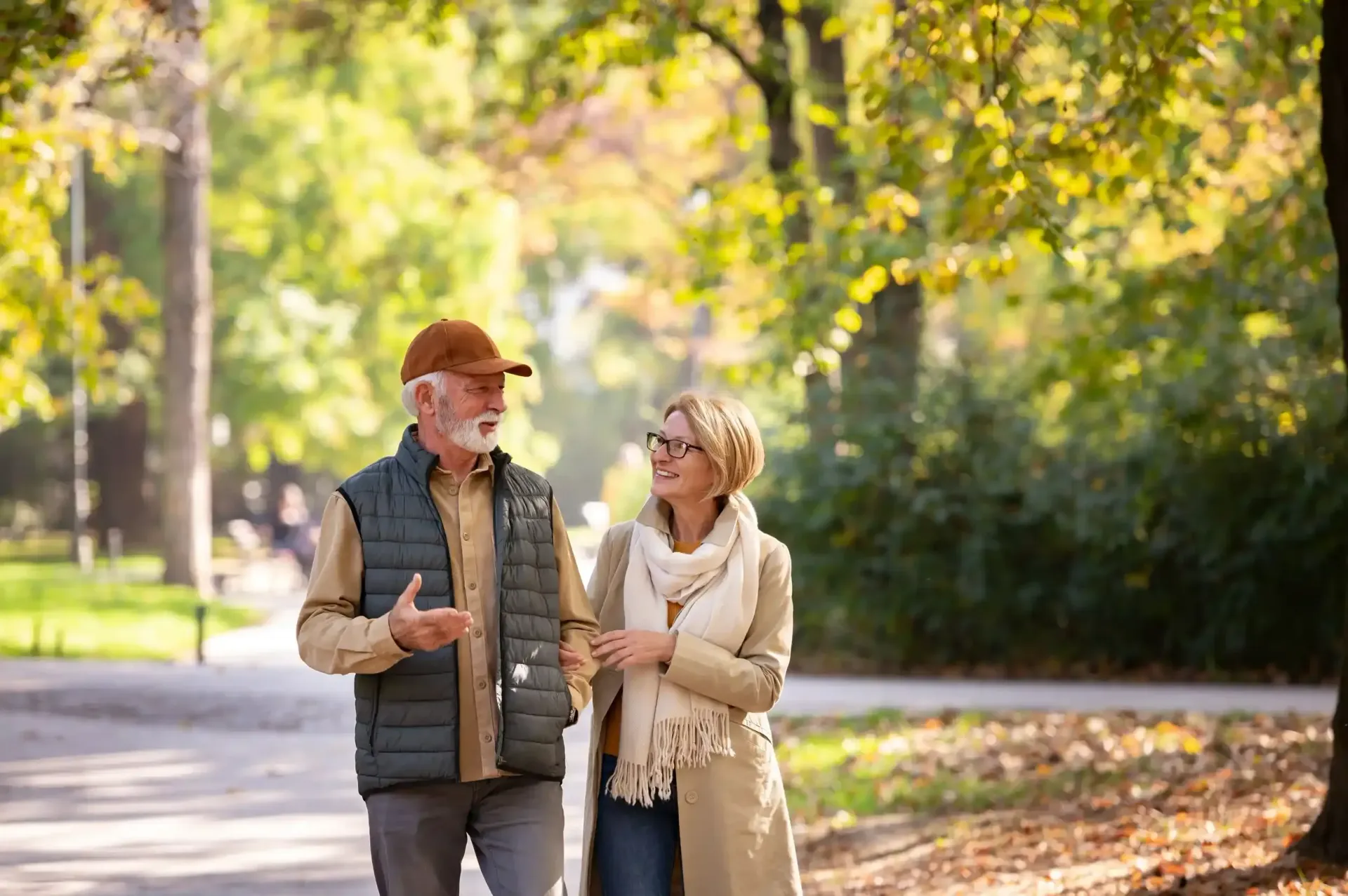 An elderly couple is walking in a park.