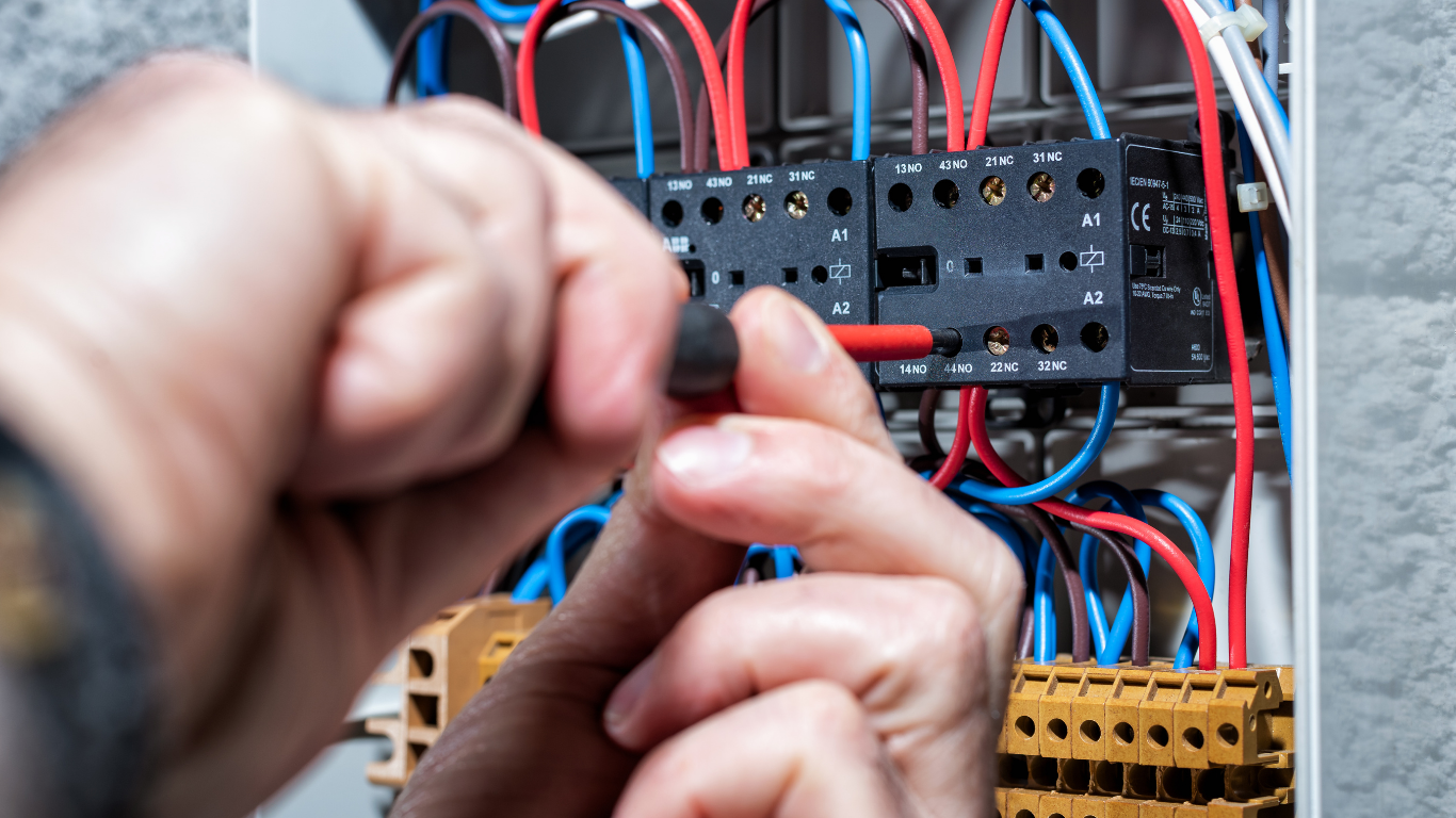 Electrician testing a circuit breaker panel with a multimeter and screwdriver