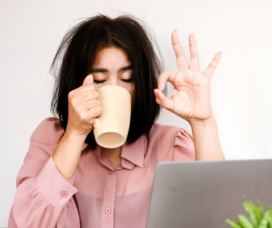 Tired woman drinking from a mug with messy hair, giving the