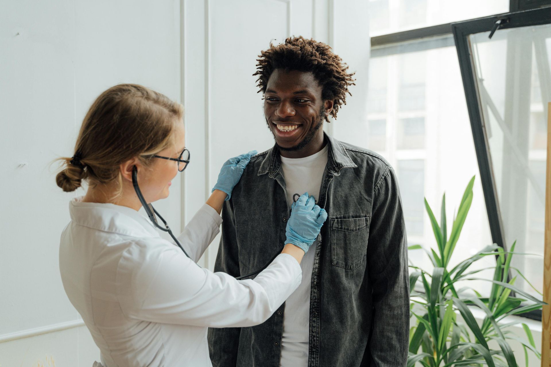 picture of doctor using a stethoscope to examine a smiling patient.