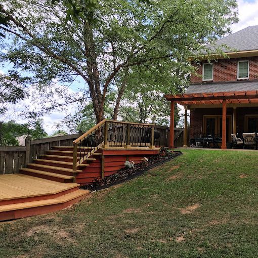 A brick house with a wooden deck and stairs in front of it.
