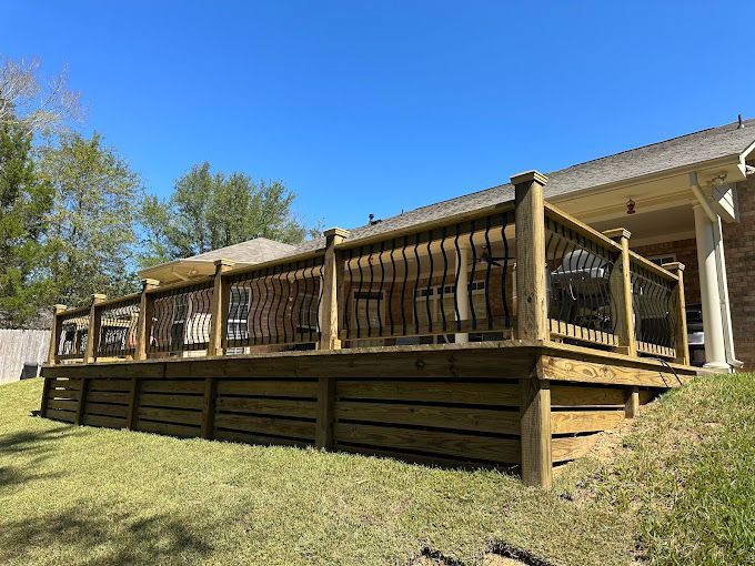 A large wooden deck is sitting on top of a grassy hill in front of a house.