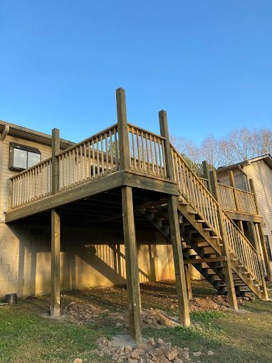 A wooden deck with stairs leading up to it is in front of a house.