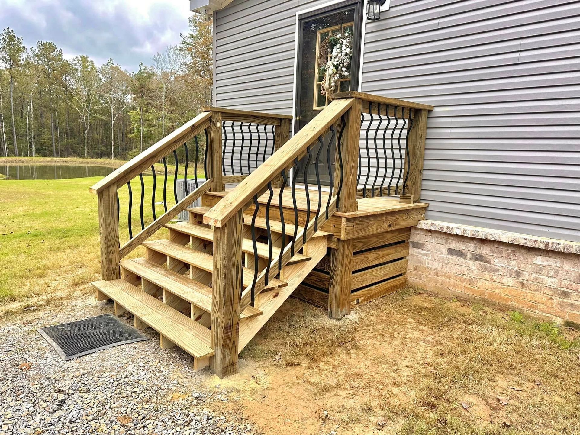 A wooden deck with stairs leading up to the front door of a house.