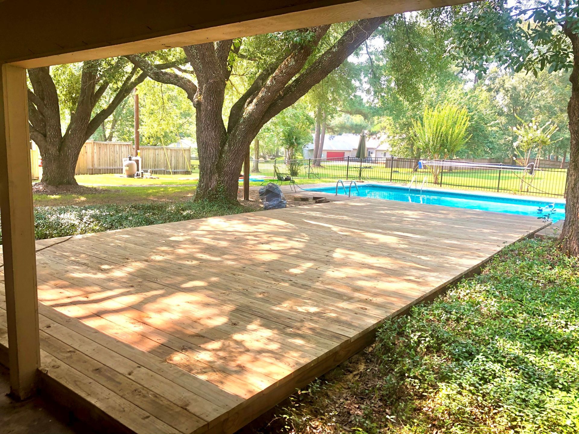 A wooden deck with a swimming pool in the background.