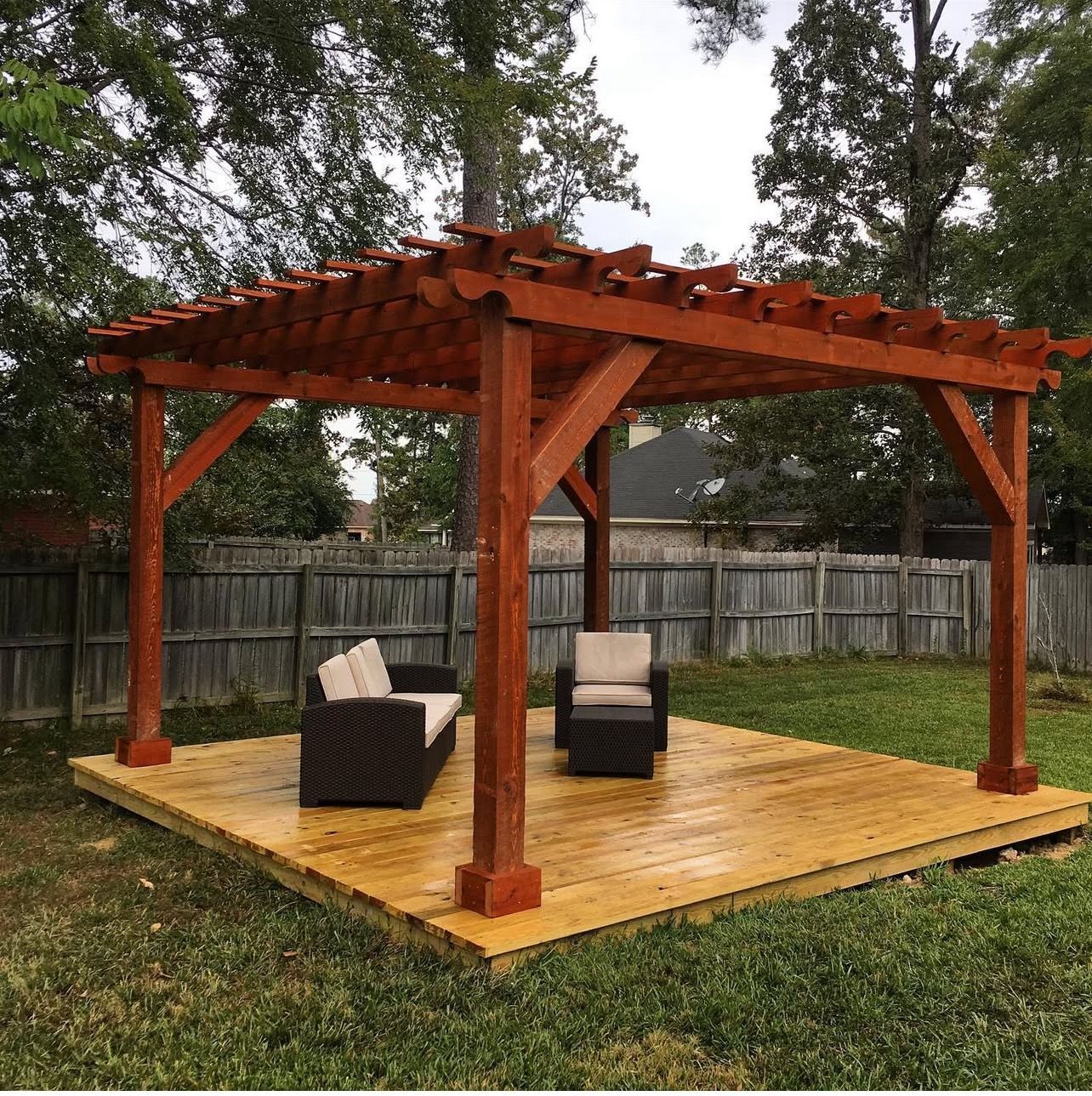 A wooden pergola with chairs and a couch underneath it