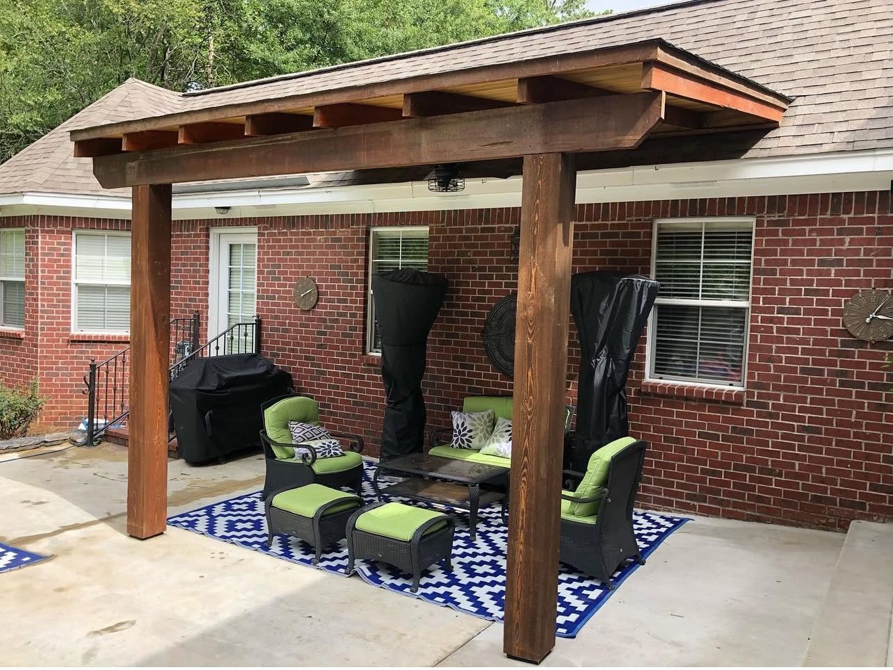 A brick house with a wooden pergola and patio furniture.