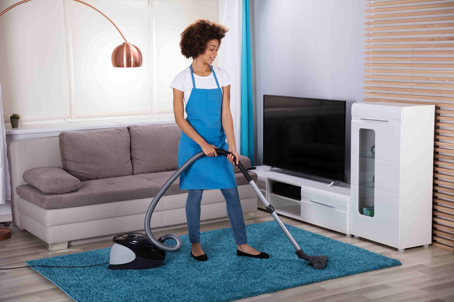 a woman is vacuuming a blue rug in a living room