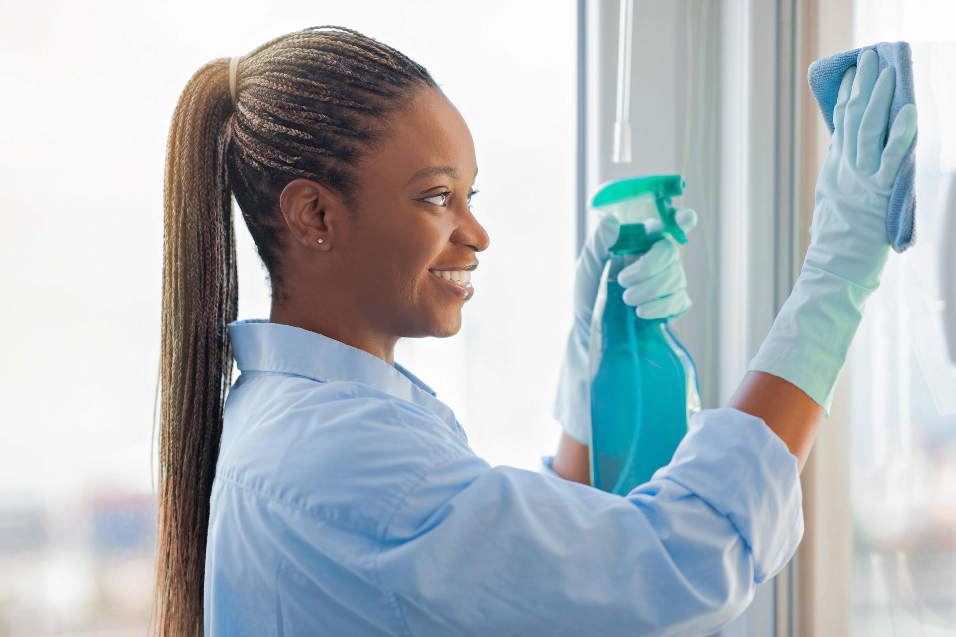 a woman is cleaning a window with a spray bottle and a cloth