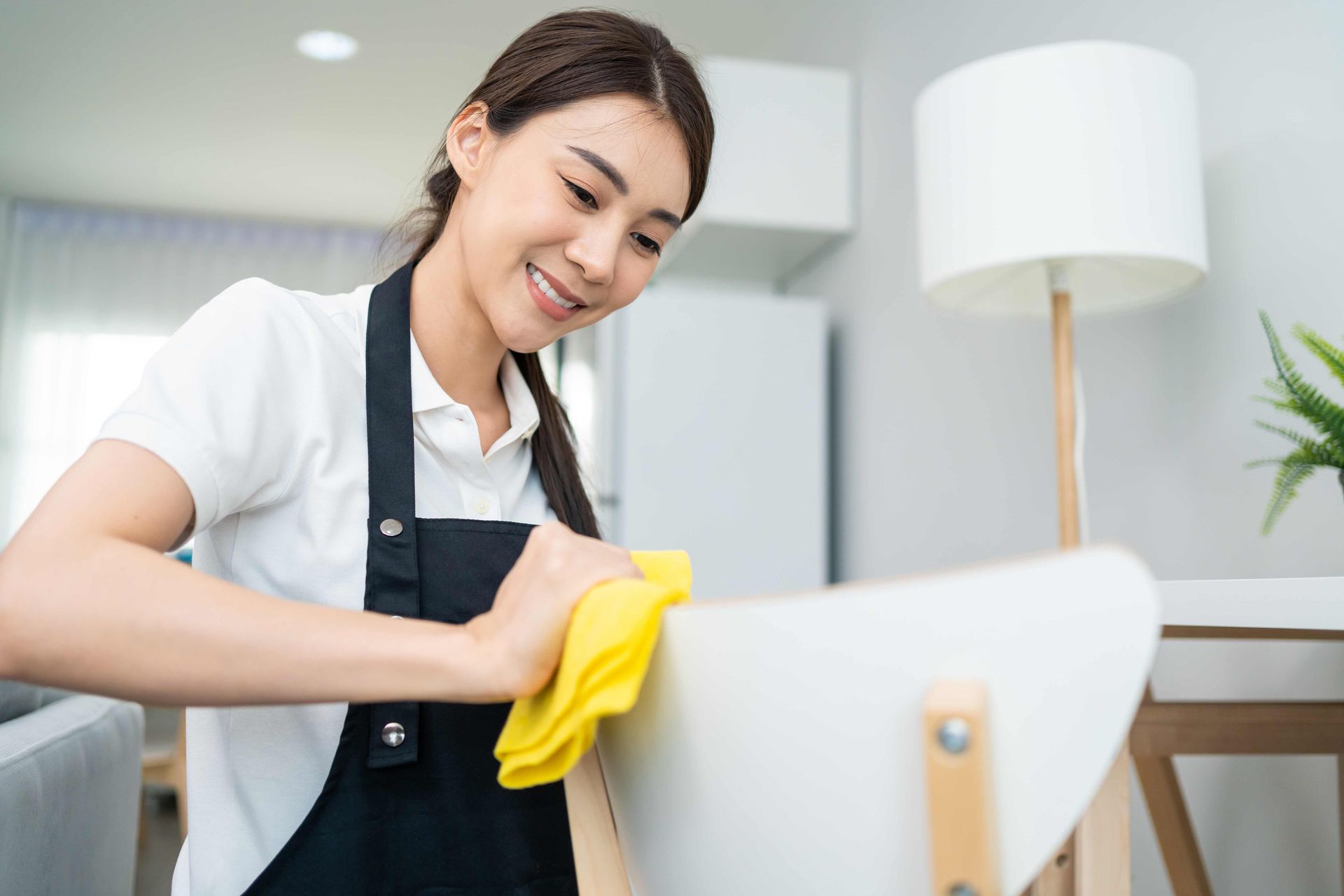 a woman in an apron is cleaning a chair with a yellow cloth 