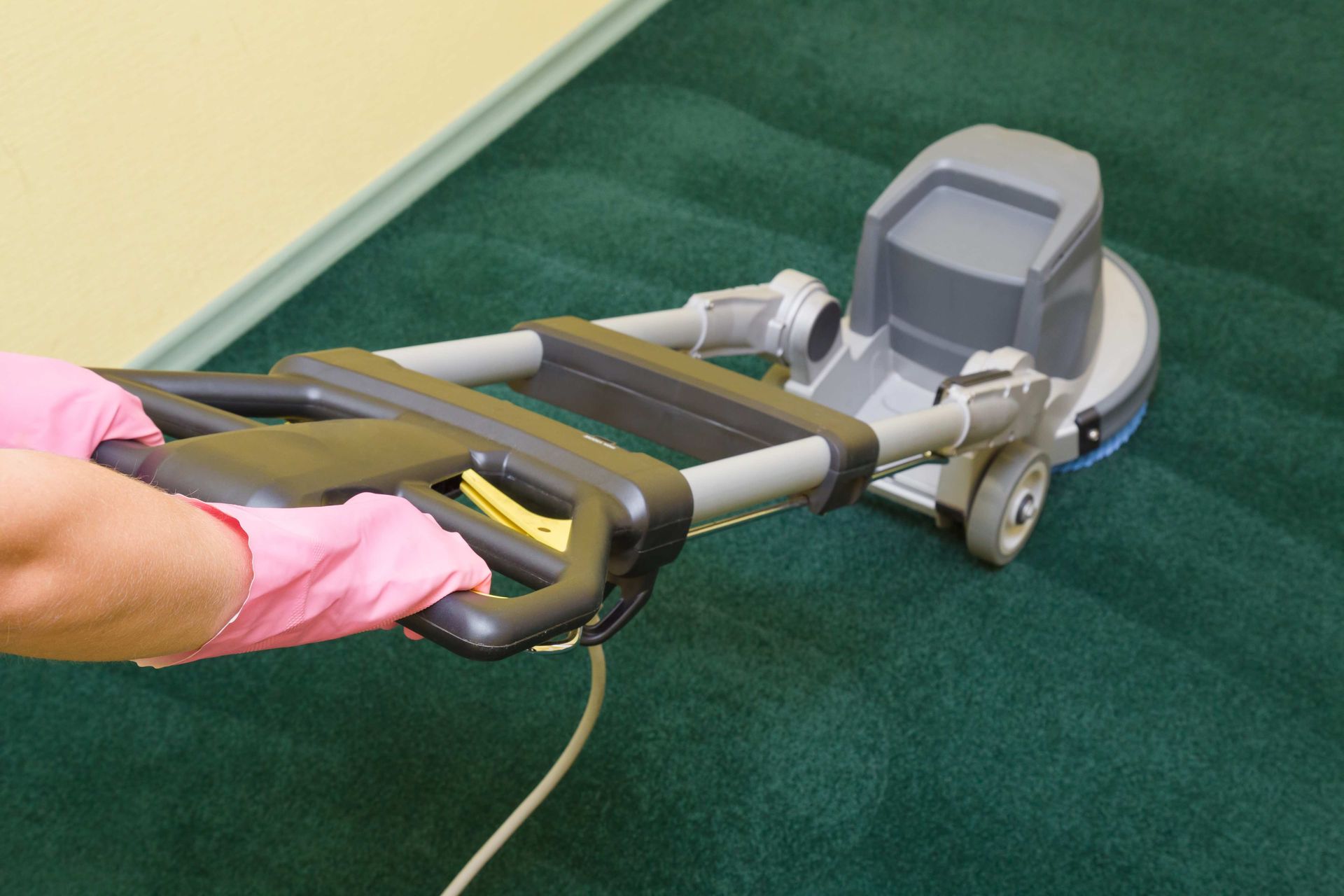 a person is using a machine to clean a green carpet