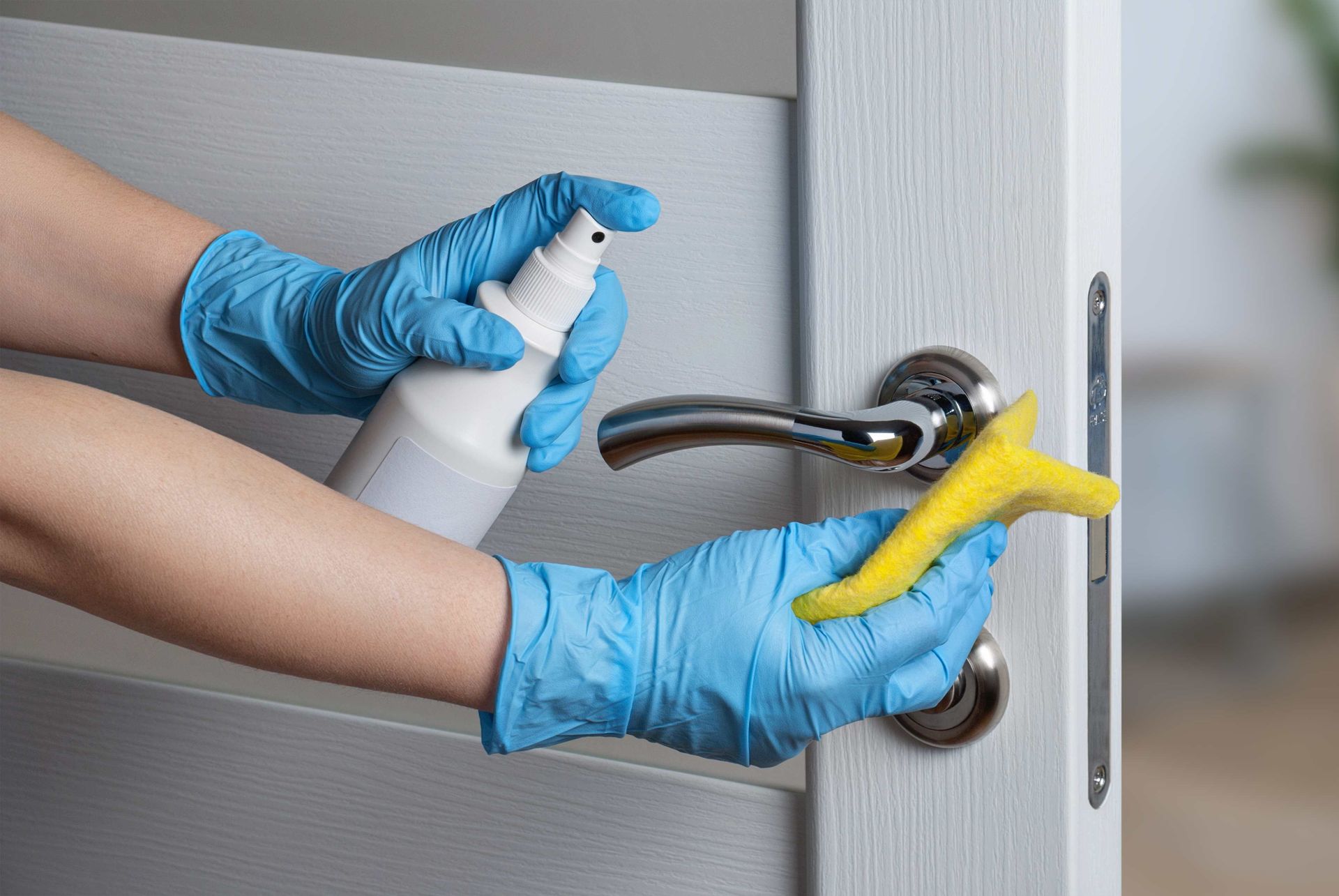 a person wearing blue gloves is cleaning a door handle with a sponge