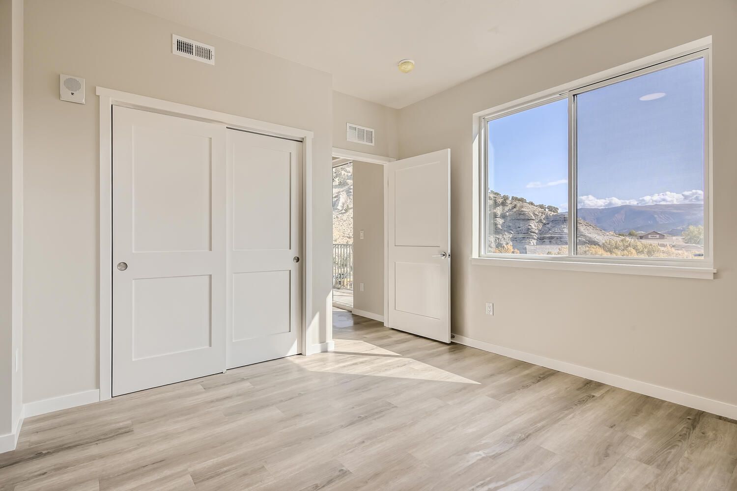 an empty bedroom with sliding doors and a large window