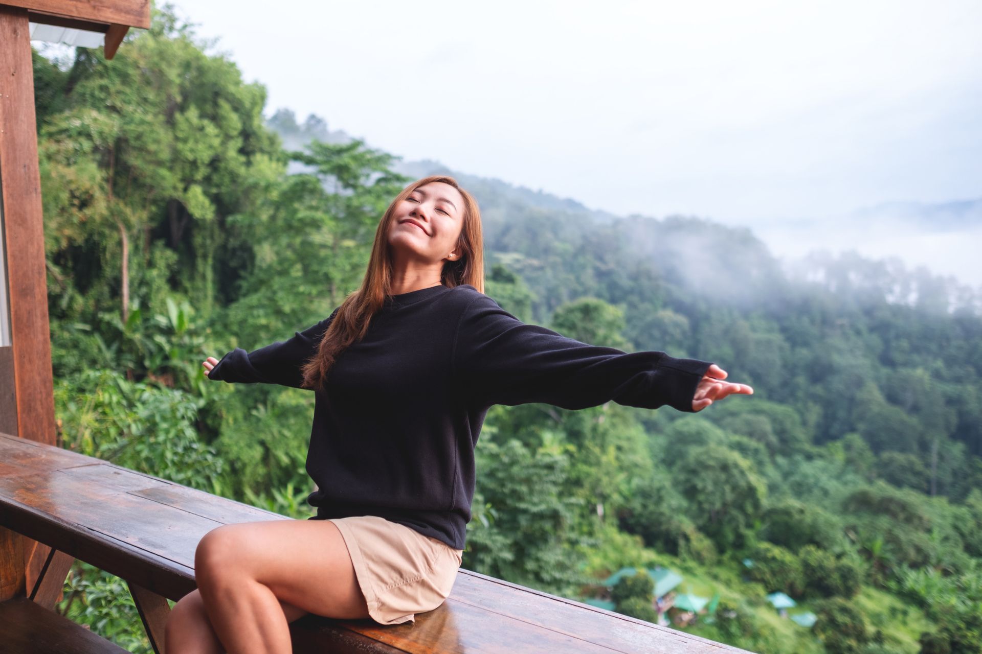 a woman sitting on a bench with her arms outstretched