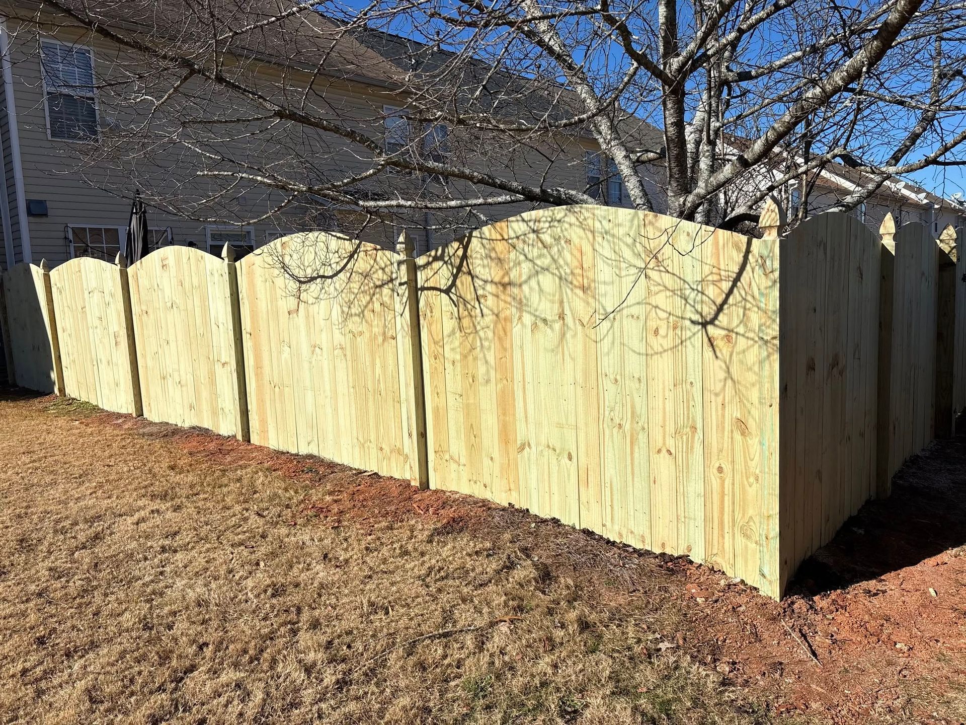 A wooden fence is in the backyard of a house.