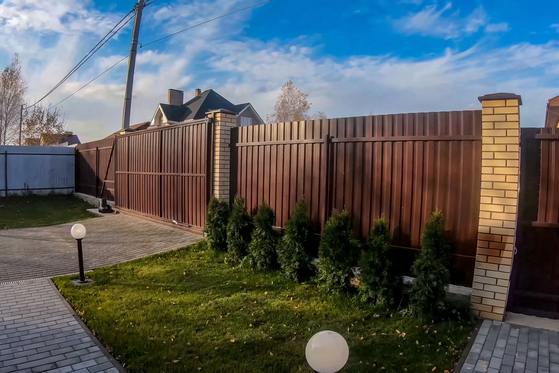 A vinyl fence surrounds a lush green garden.