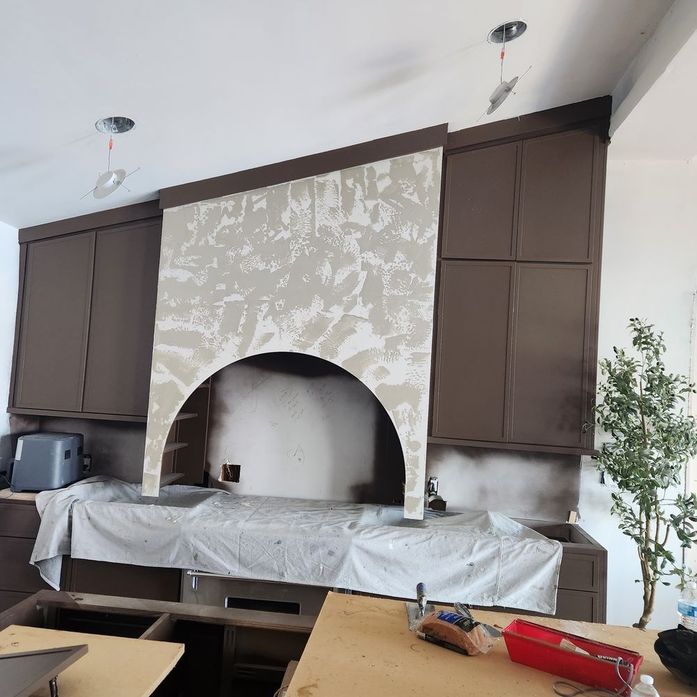 Kitchen remodel with brown cabinets, range hood, and plastic sheeting.