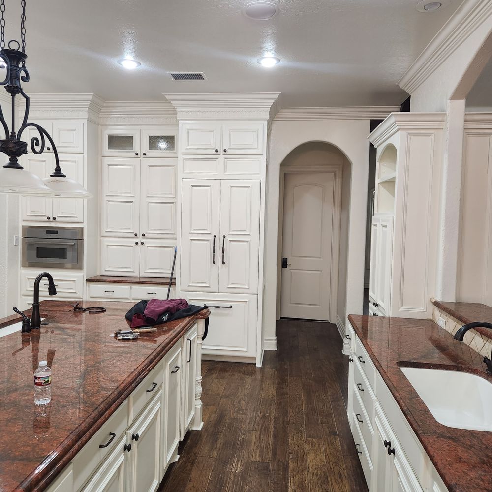 White kitchen with granite countertops, dark cabinets, and wooden floors.
