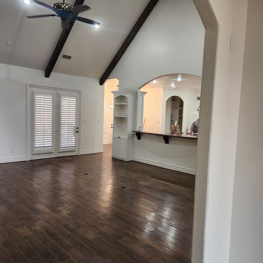 Spacious room with hardwood floors, vaulted ceiling, arched doorway, and built-in shelving.