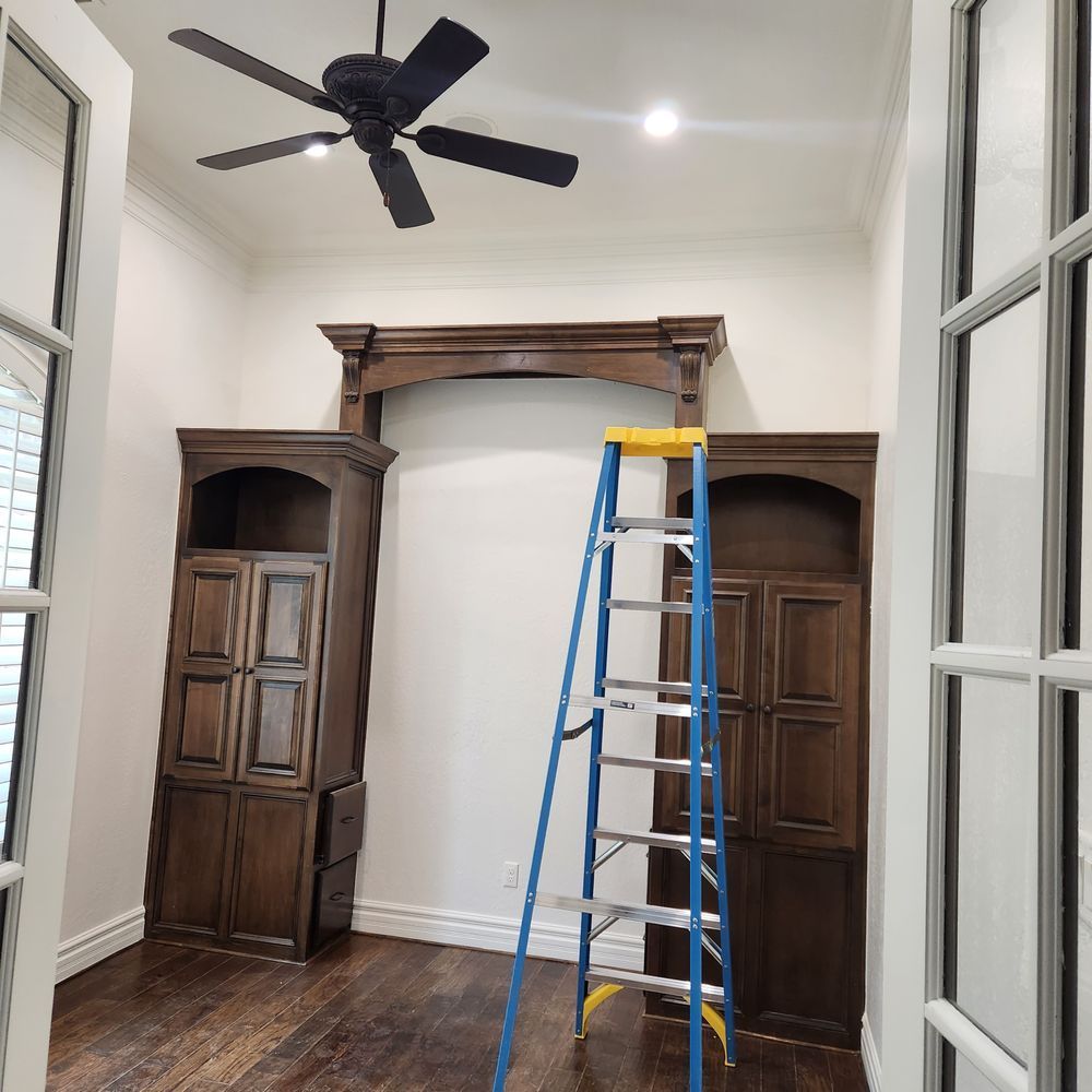 Interior with built-in dark wood cabinets, arched top, ladder, and ceiling fan.