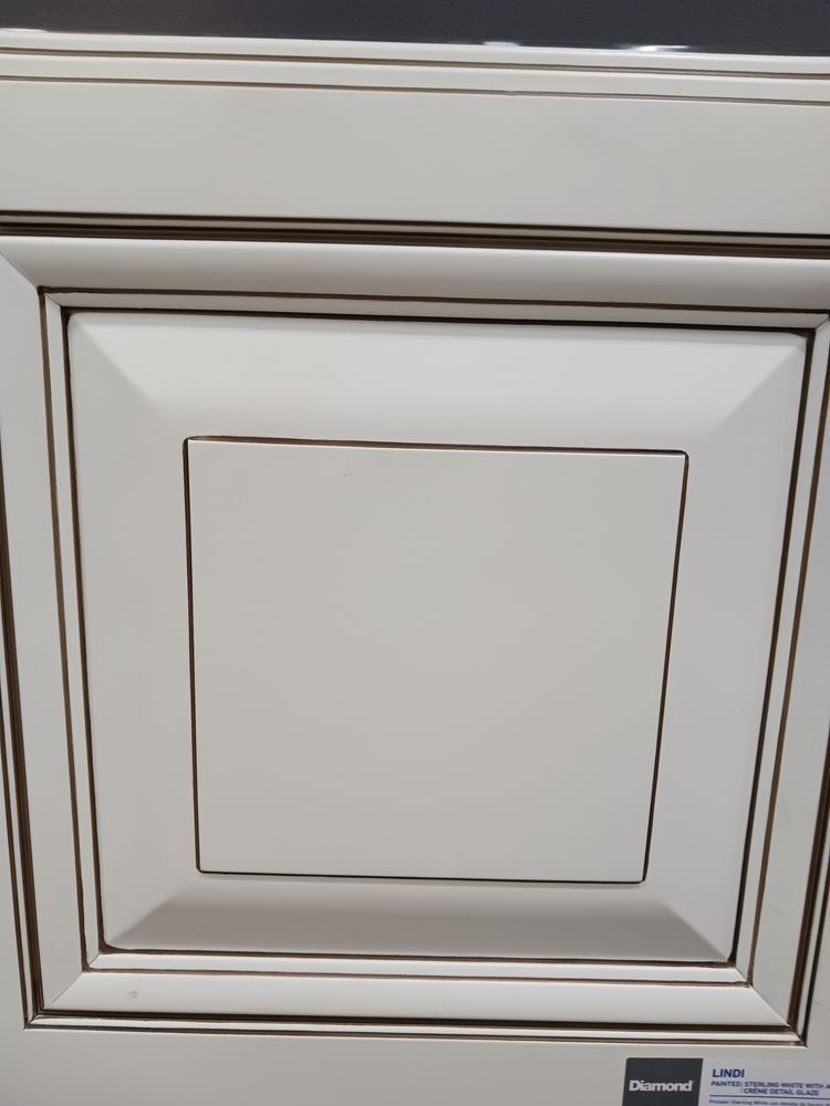 Cream-colored kitchen cabinet door with square inset, and brown trim.