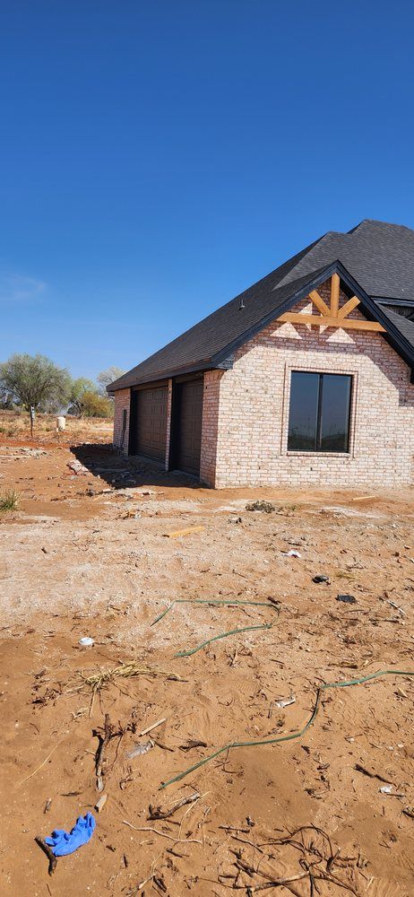 Brick house under construction against a clear blue sky.