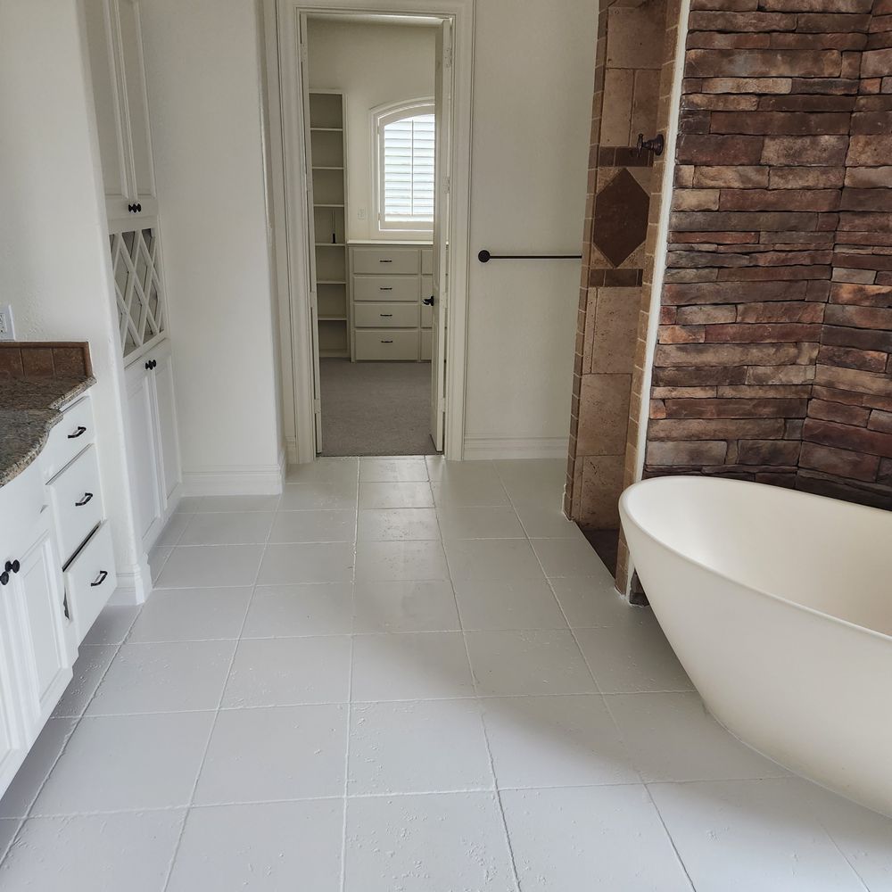 Bathroom with white cabinets, stone wall, and a freestanding tub. A doorway leads to a closet.