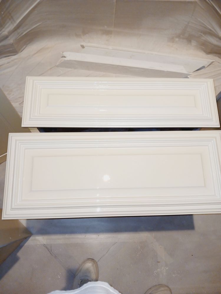 Two freshly painted, light-colored cabinet doors, resting on a drop cloth.