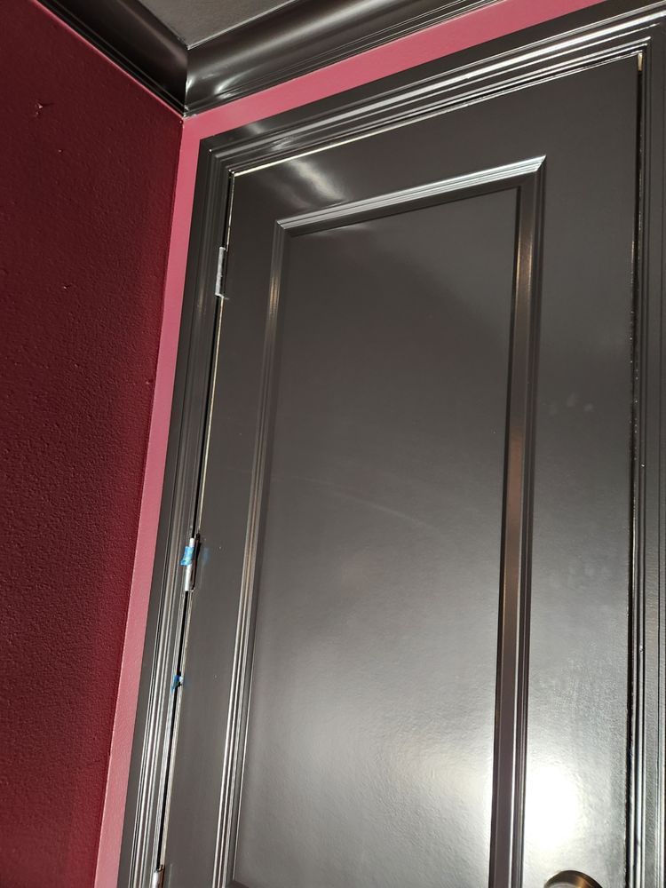 Silver door with matching trim against a red wall.