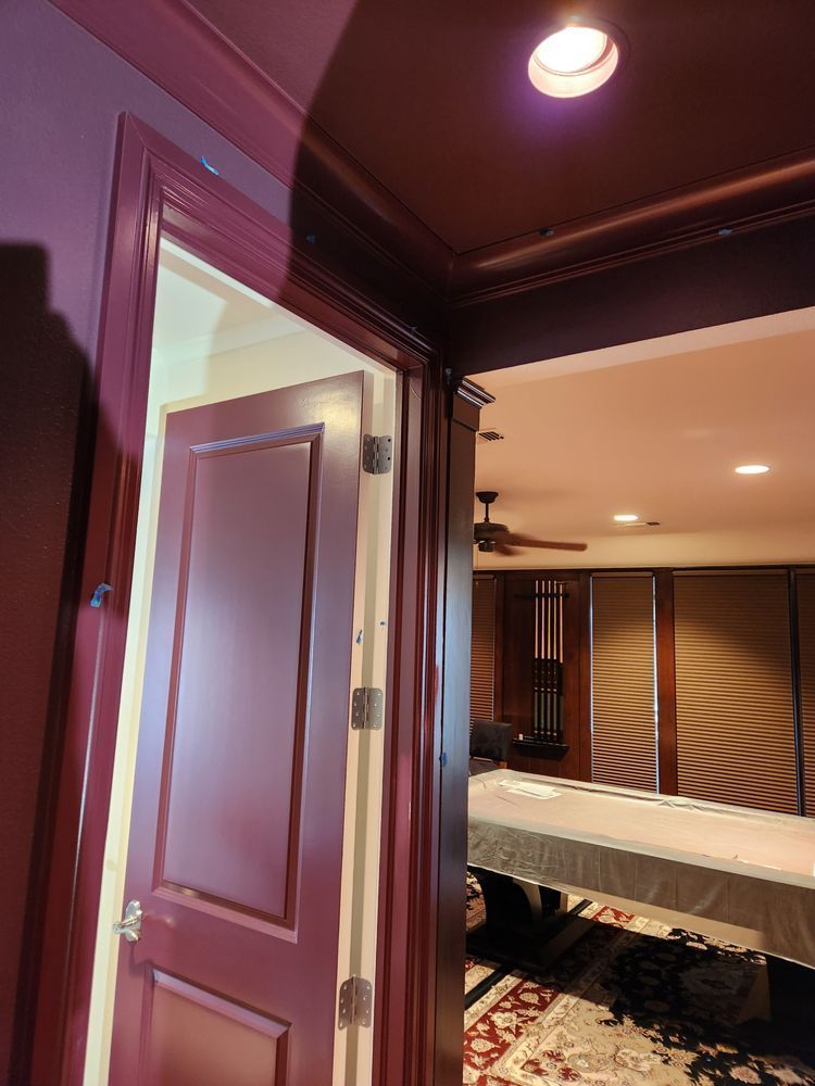 Doorway leading into a room. Burgundy door, dark wood trim, and a room with a pool table and dark accents.