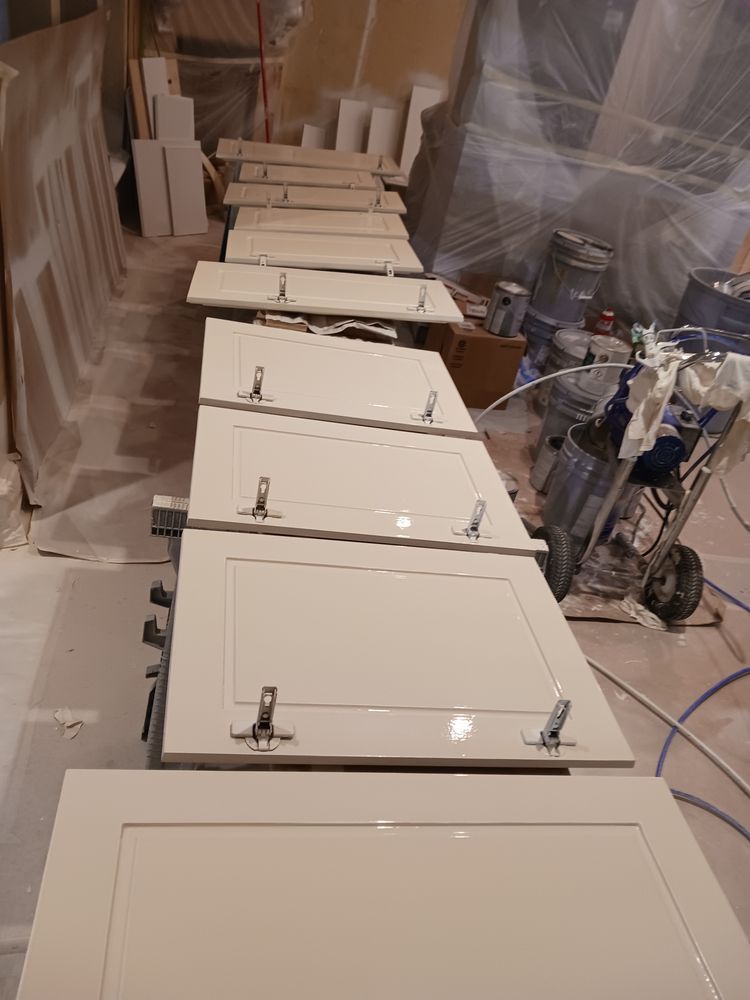 Cabinet doors laid out, painted beige, in a workshop ready for assembly.