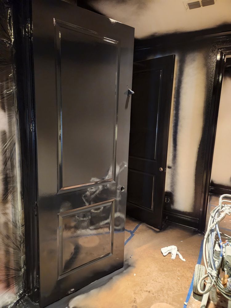 Two black doors in a room with black trim, possibly being painted.