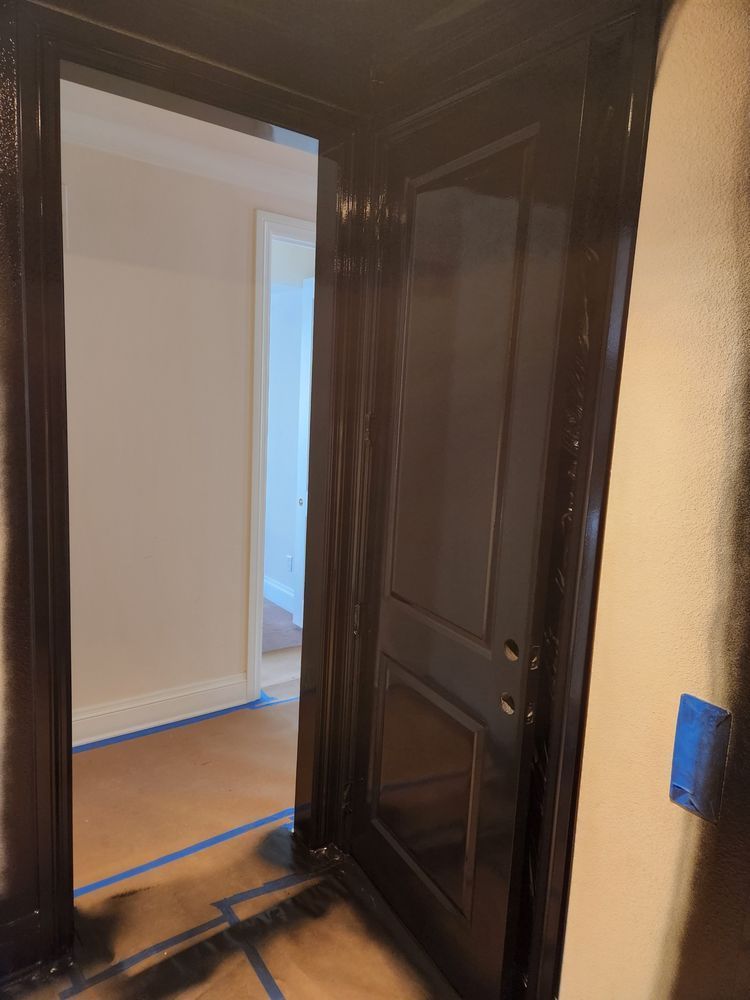 Dark stained door frame and door in a hallway. Brown wood, cream walls, blue tape.
