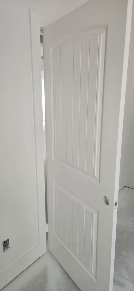 White interior door slightly ajar in a white room, showing a door and frame.