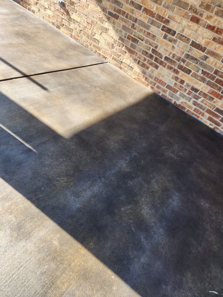 Concrete patio with a brick wall. Shadows cast by sunlight on a textured surface.