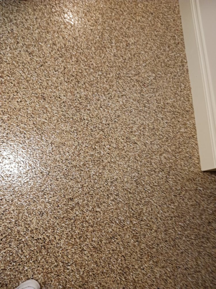 Tan speckled flooring with a hint of shine, near a white door frame.