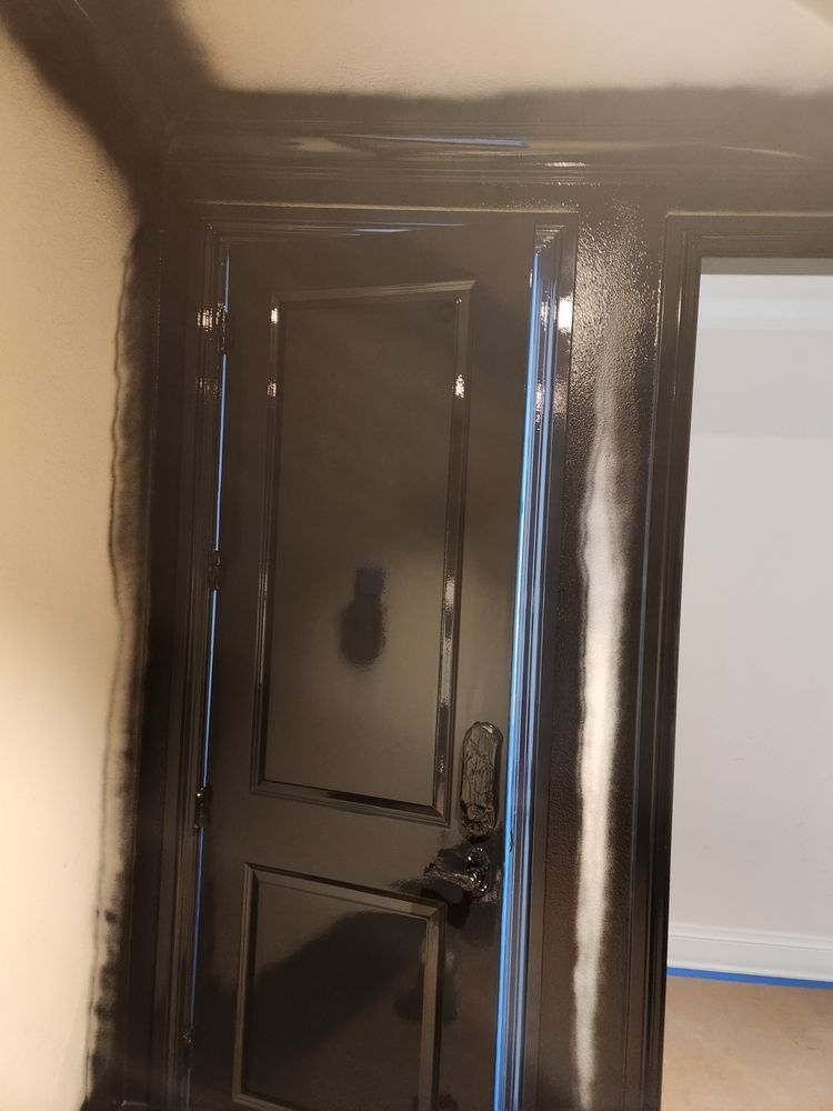 Black painted door and trim against white wall. Door handle and lock visible.