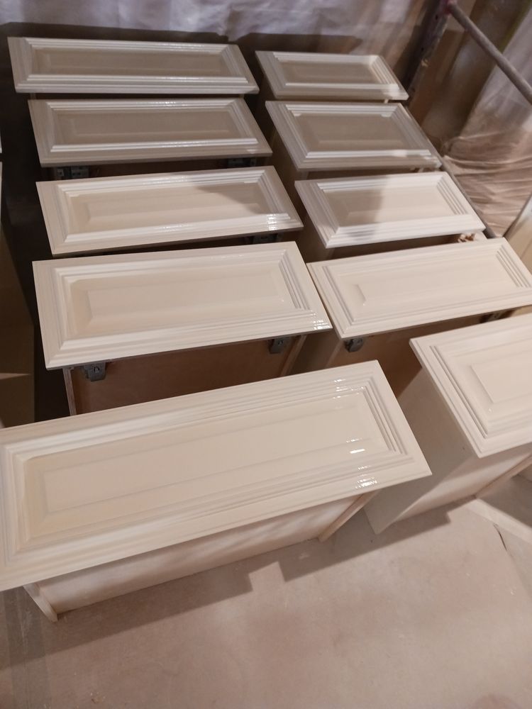 Light beige kitchen cabinet doors and drawers, freshly painted and drying.