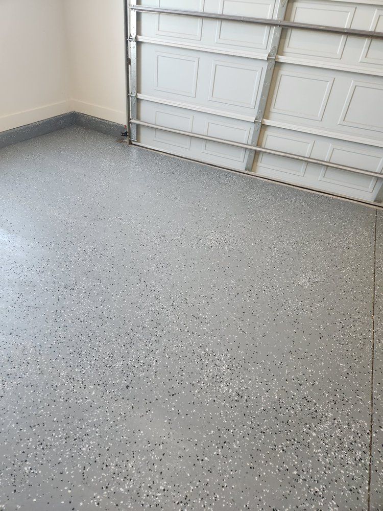 Garage with a gray epoxy floor, white garage door, and light-colored walls.