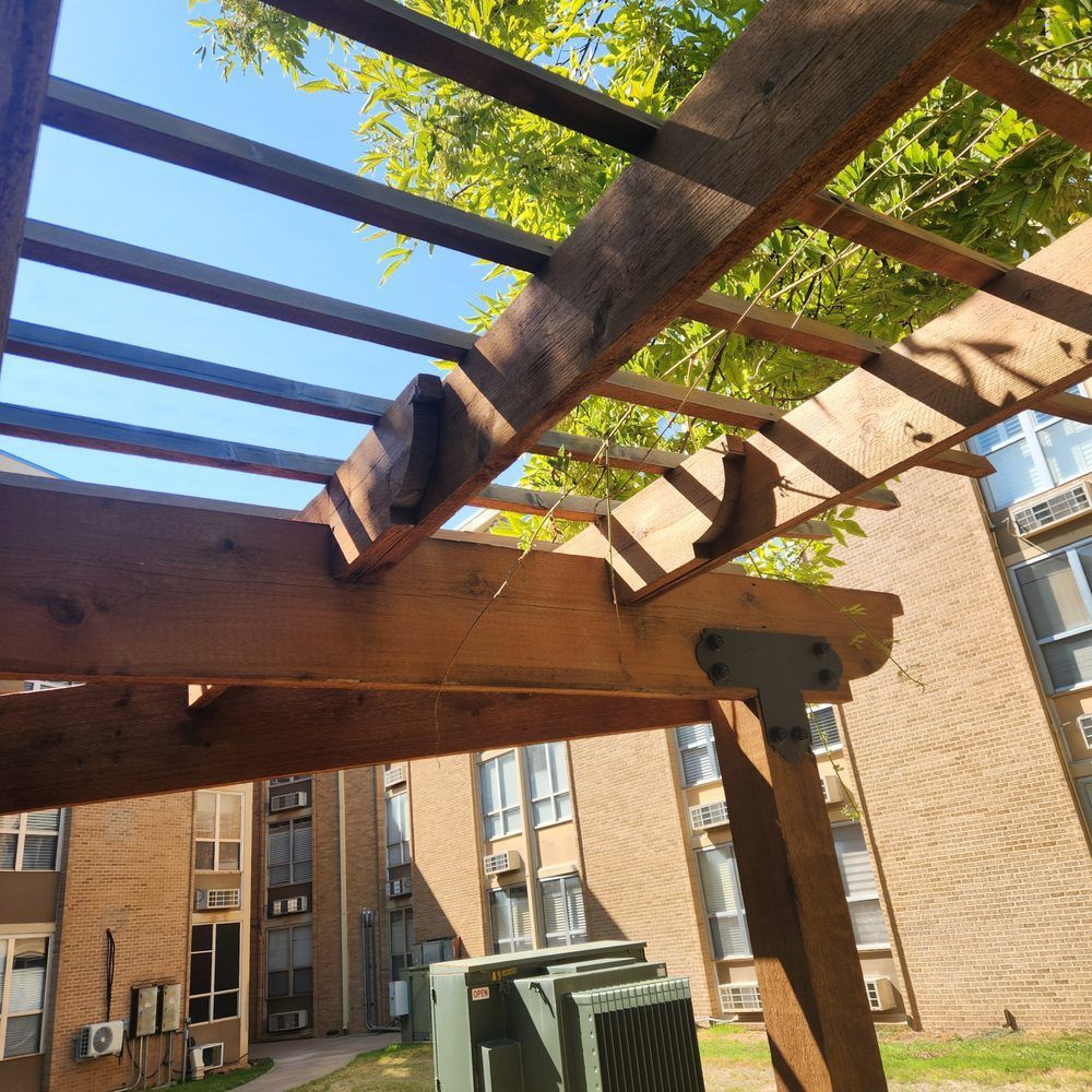 Wooden pergola with a blue sky background, over an apartment building.