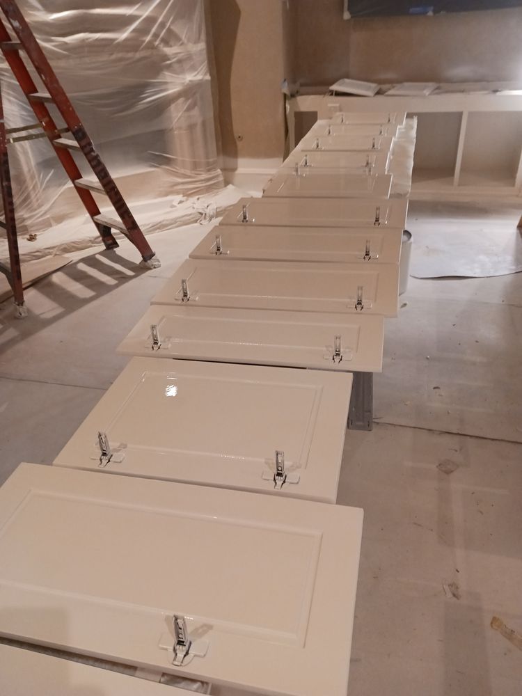 Painted cabinet doors laid out for drying in a workshop, propped up with hardware.