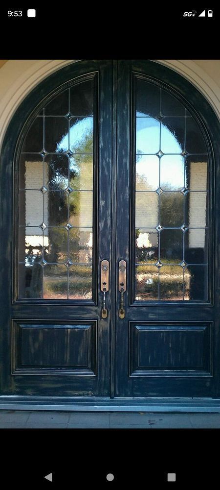 Dark blue double doors with arched top and leaded glass panels.