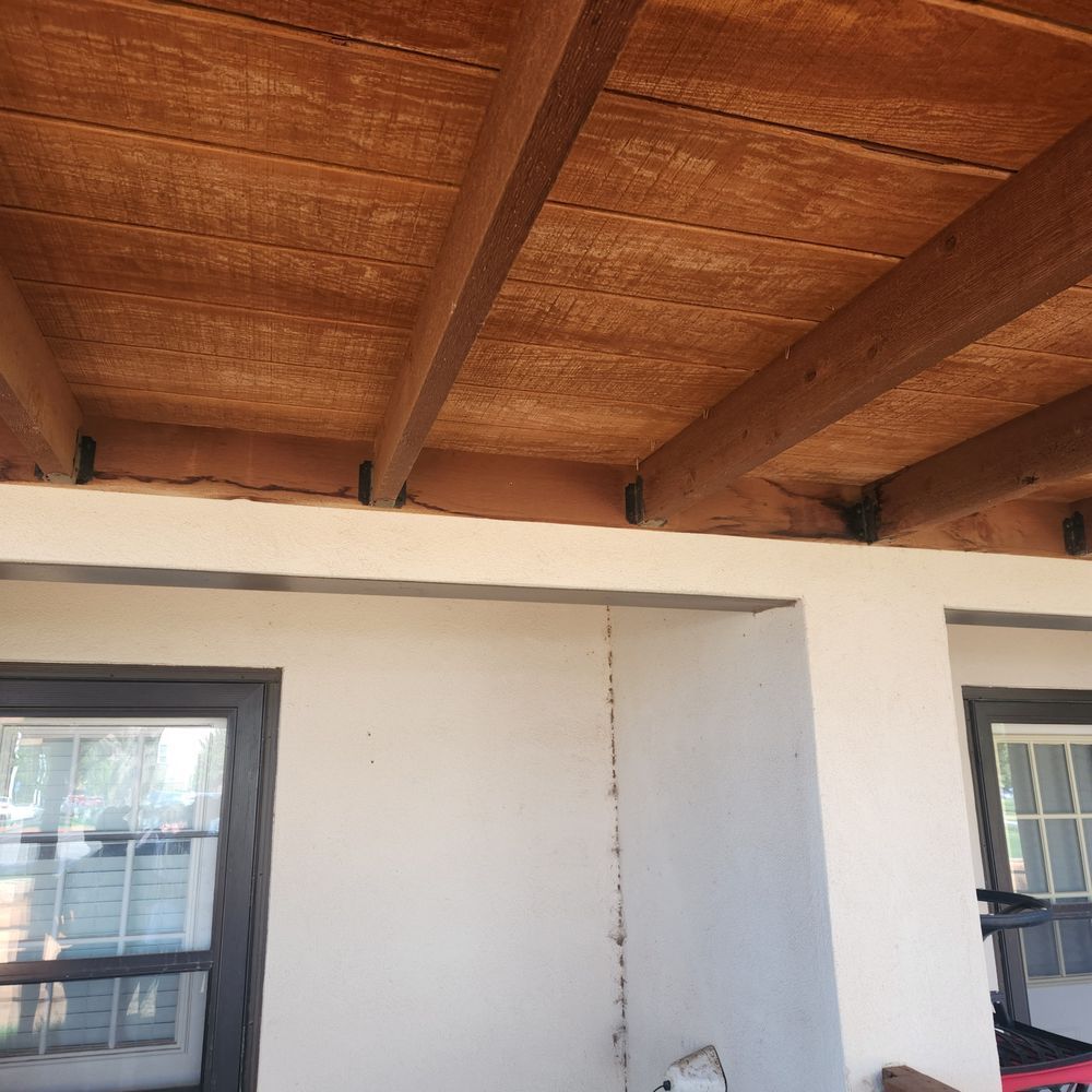 Wooden beam ceiling over white walls with black framed windows.