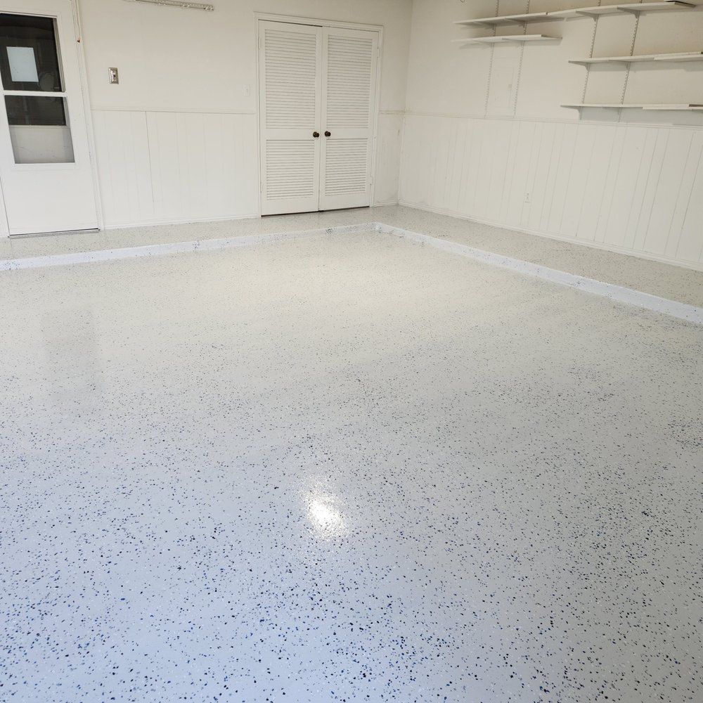 White garage floor with speckled coating; white walls, door, and shelves.