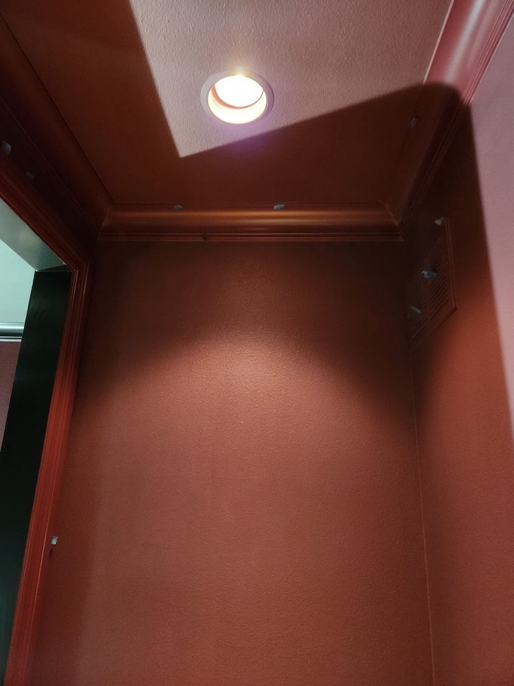 Red-walled alcove with recessed ceiling light illuminating the wall. Dark red trim.