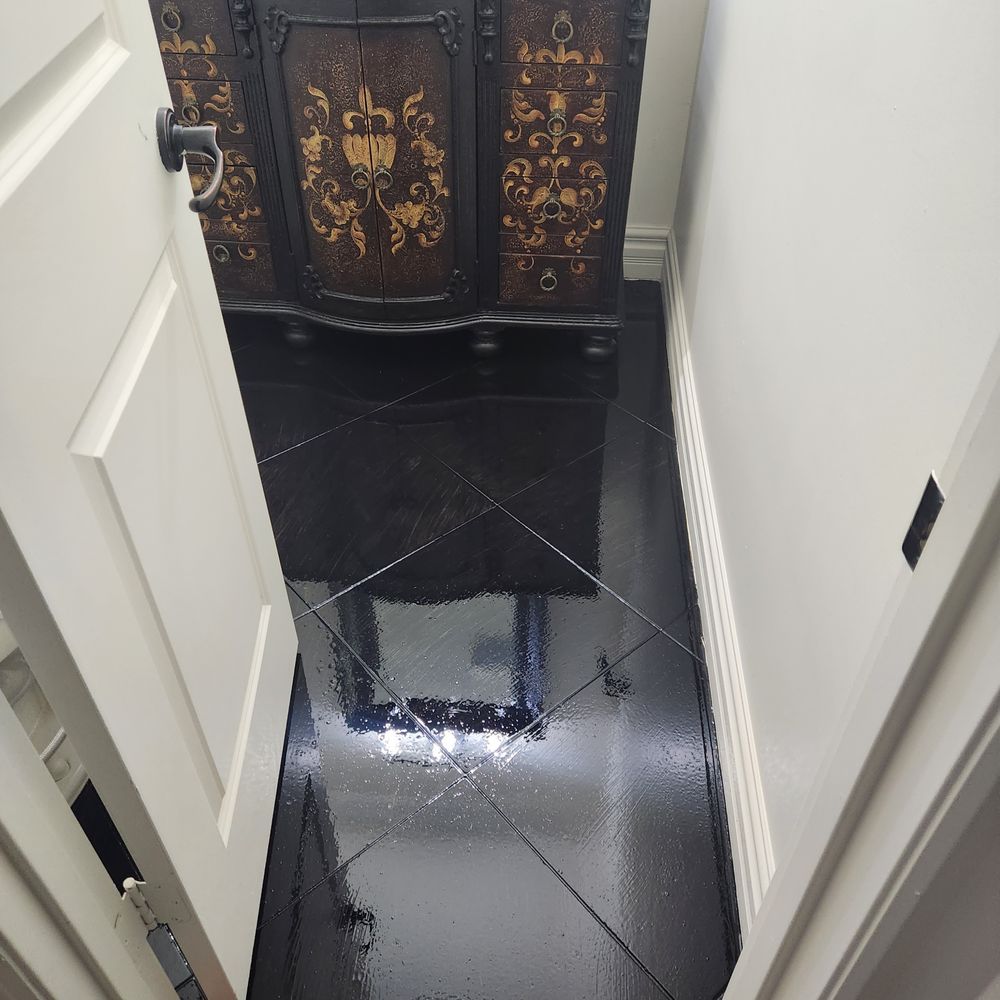 Black tiled hallway with white trim and a decorative cabinet.